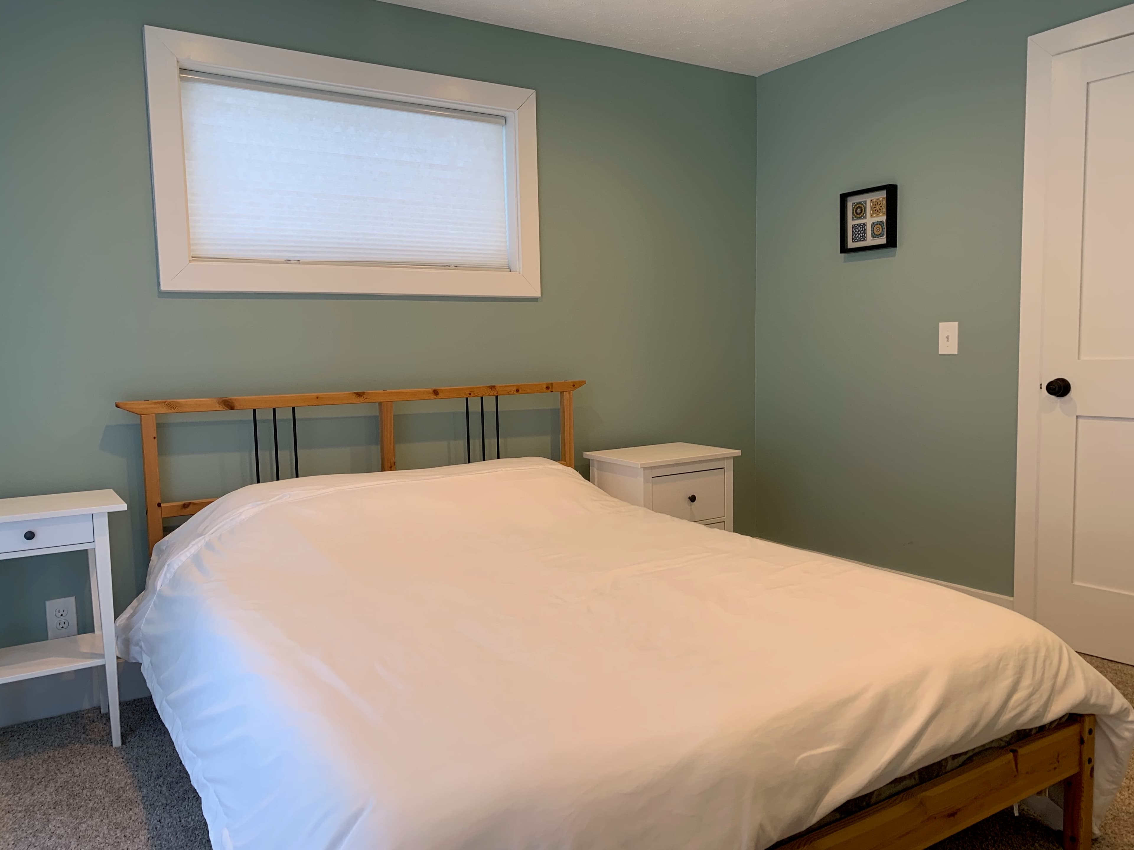 Second bedroom with queen bed, pine headboard, and white nightstands
